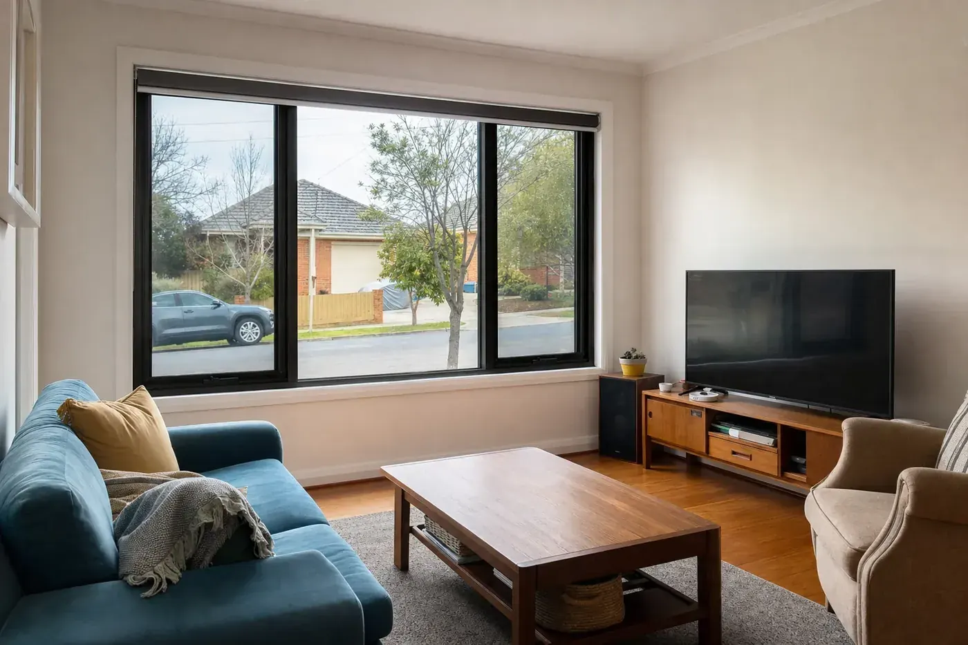 Front room of a 1960s cream brick veneer house with black aluminium double glazed windows