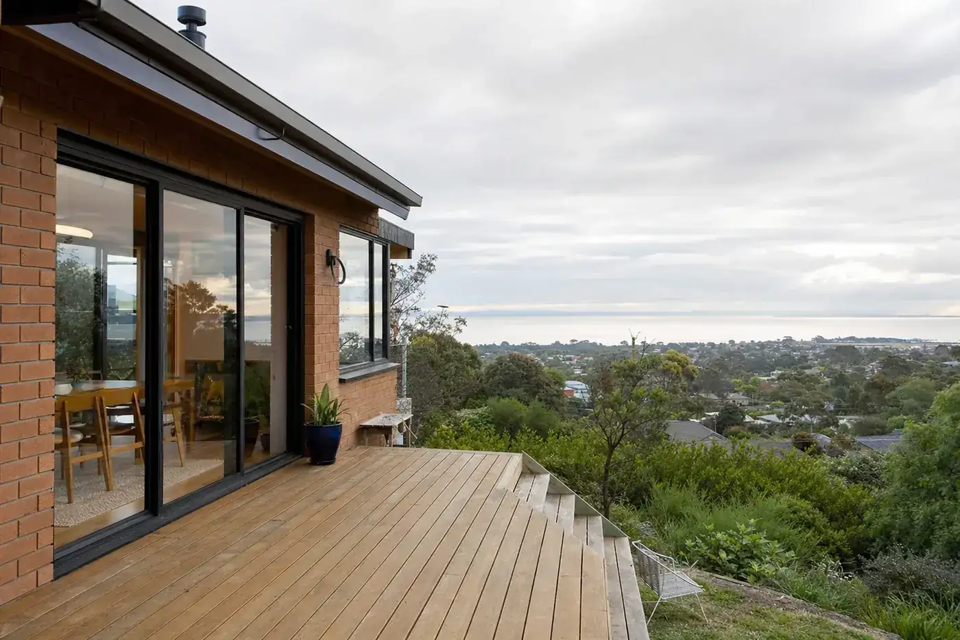 Rear of a 1970s brick house on a slope with black aluminium double glazed windows