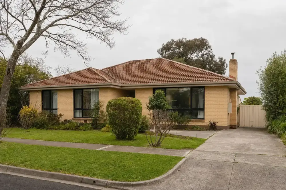 1960s cream brick veneer house on a wide block with black aluminium double glazed windows