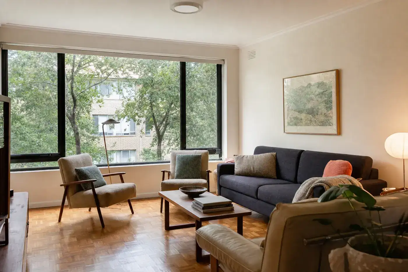 Living room of a 1960s low-rise walk-up apartment block with black aluminium double glazed windows