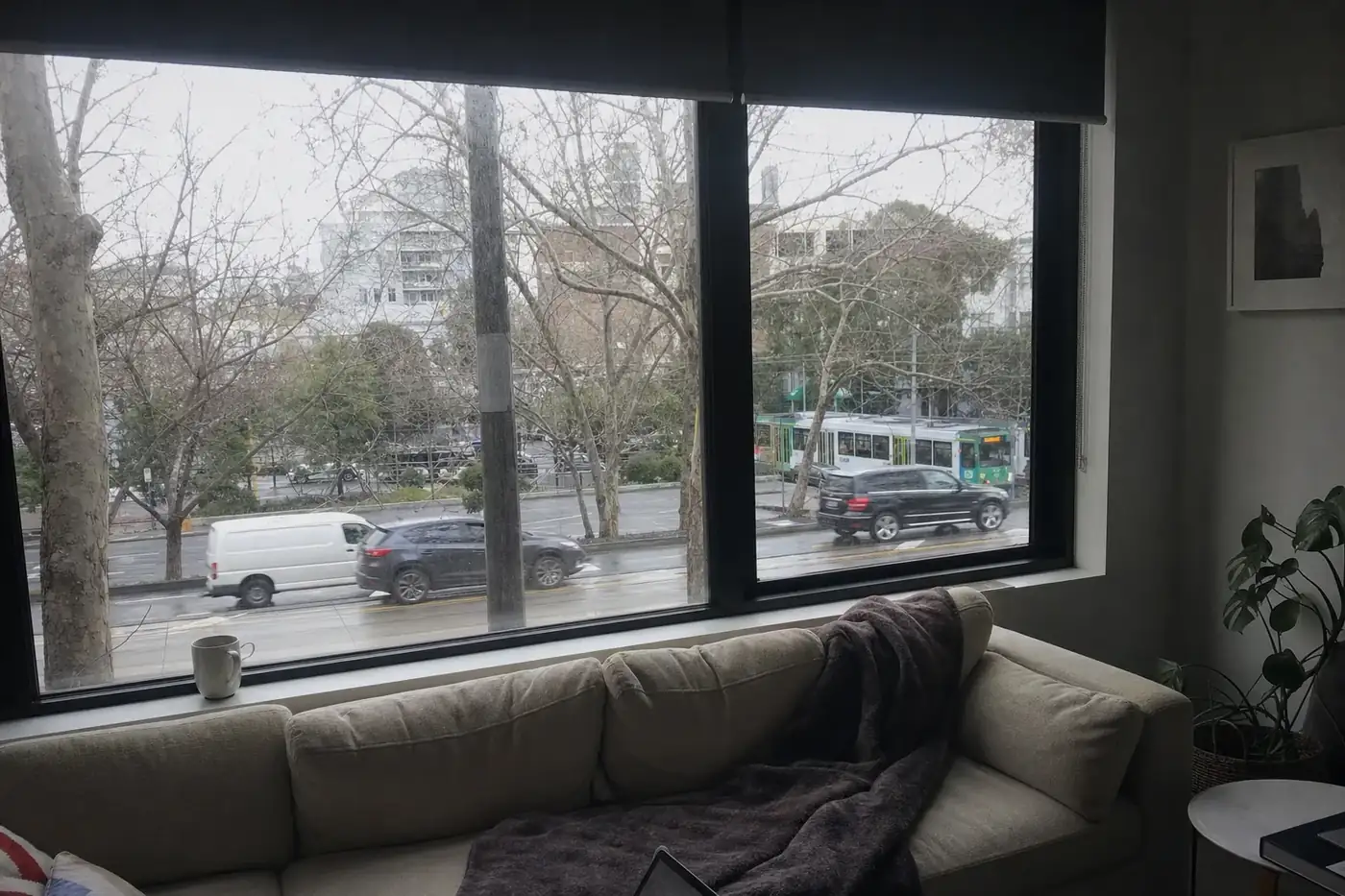 Living room on a grey winter morning with a black aluminium double glazed window facing a busy street